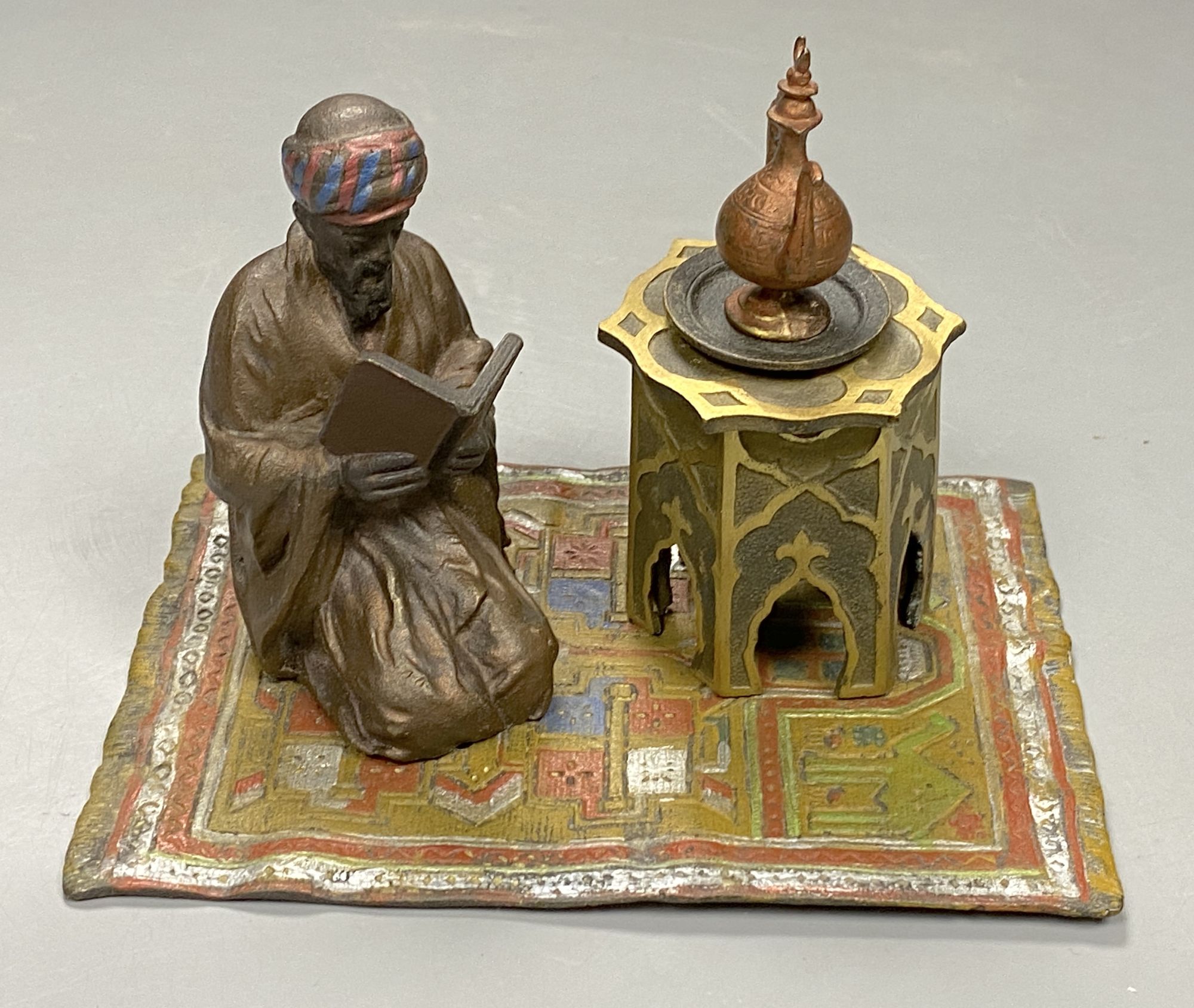A cold painted bronze desk stand modelled as a reading Arab, length 14.5cm